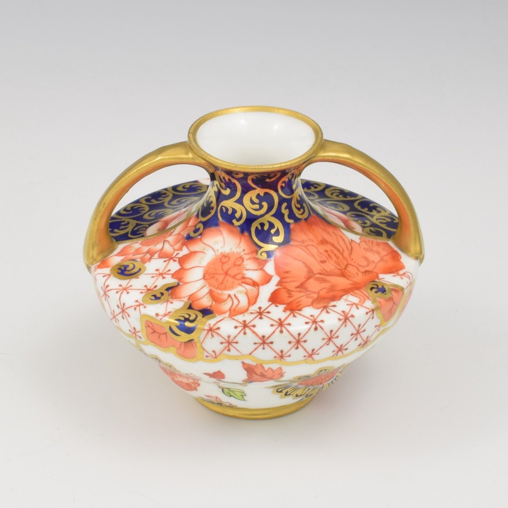 An Edwardian Royal Crown Derby miniature twin-handled porcelain vase decorated with an Imari floral pattern in cobalt blue, iron red, and gilt. View IX