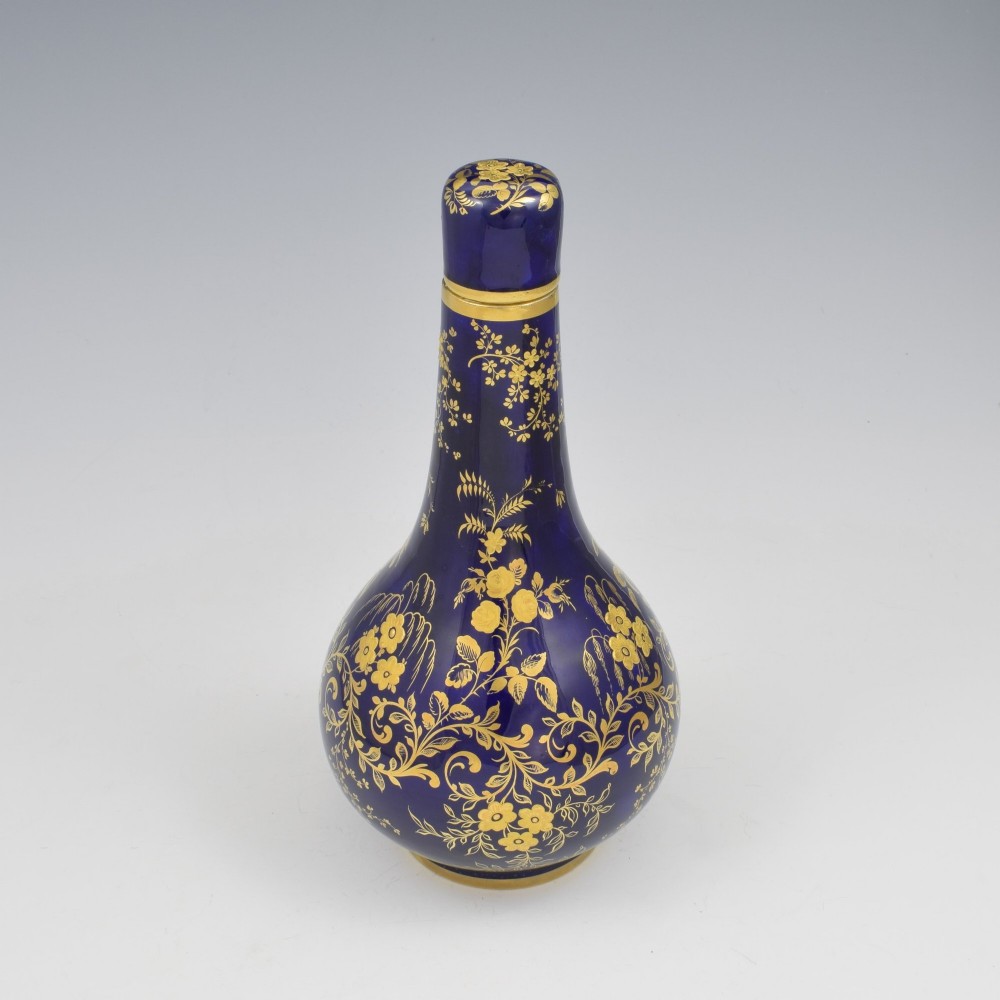 A cobalt blue porcelain bottle vase decorated with elaborate gold floral gilding and fitted with a matching rounded stopper. View II