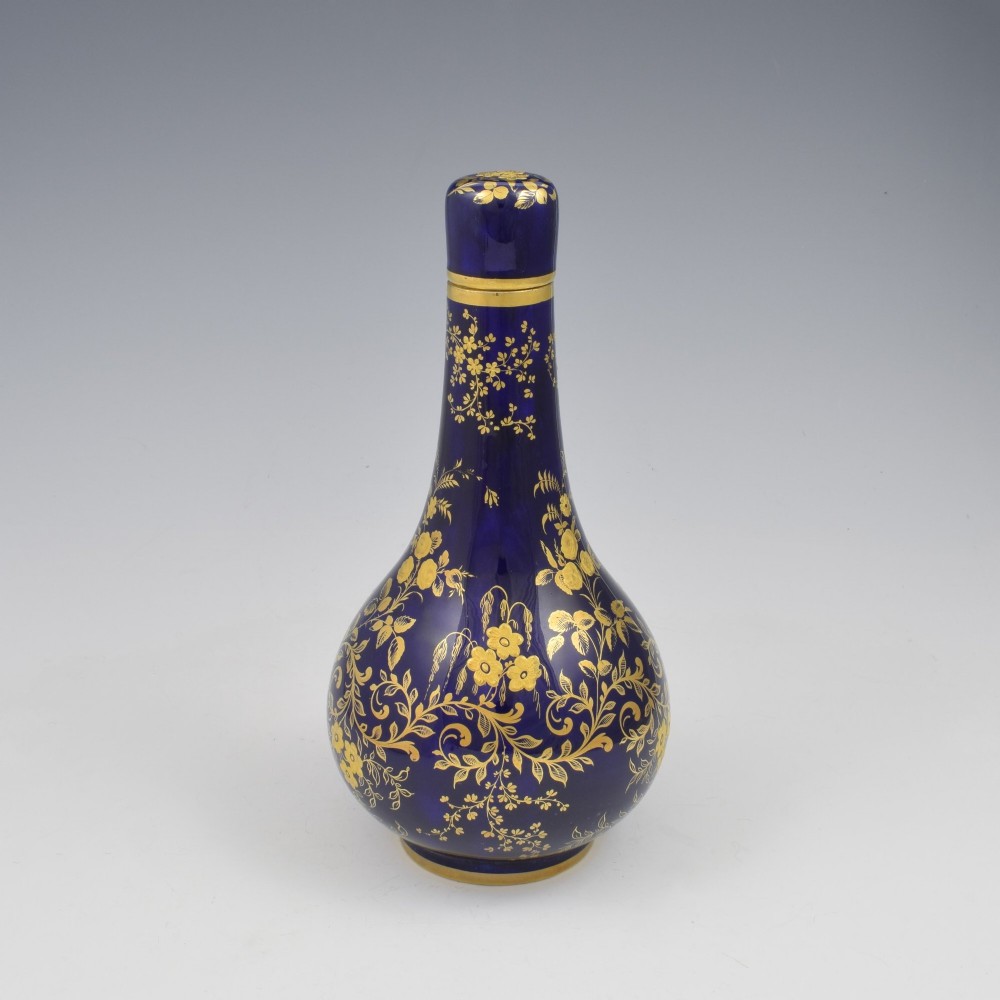 A cobalt blue porcelain bottle vase decorated with elaborate gold floral gilding and fitted with a matching rounded stopper. View III