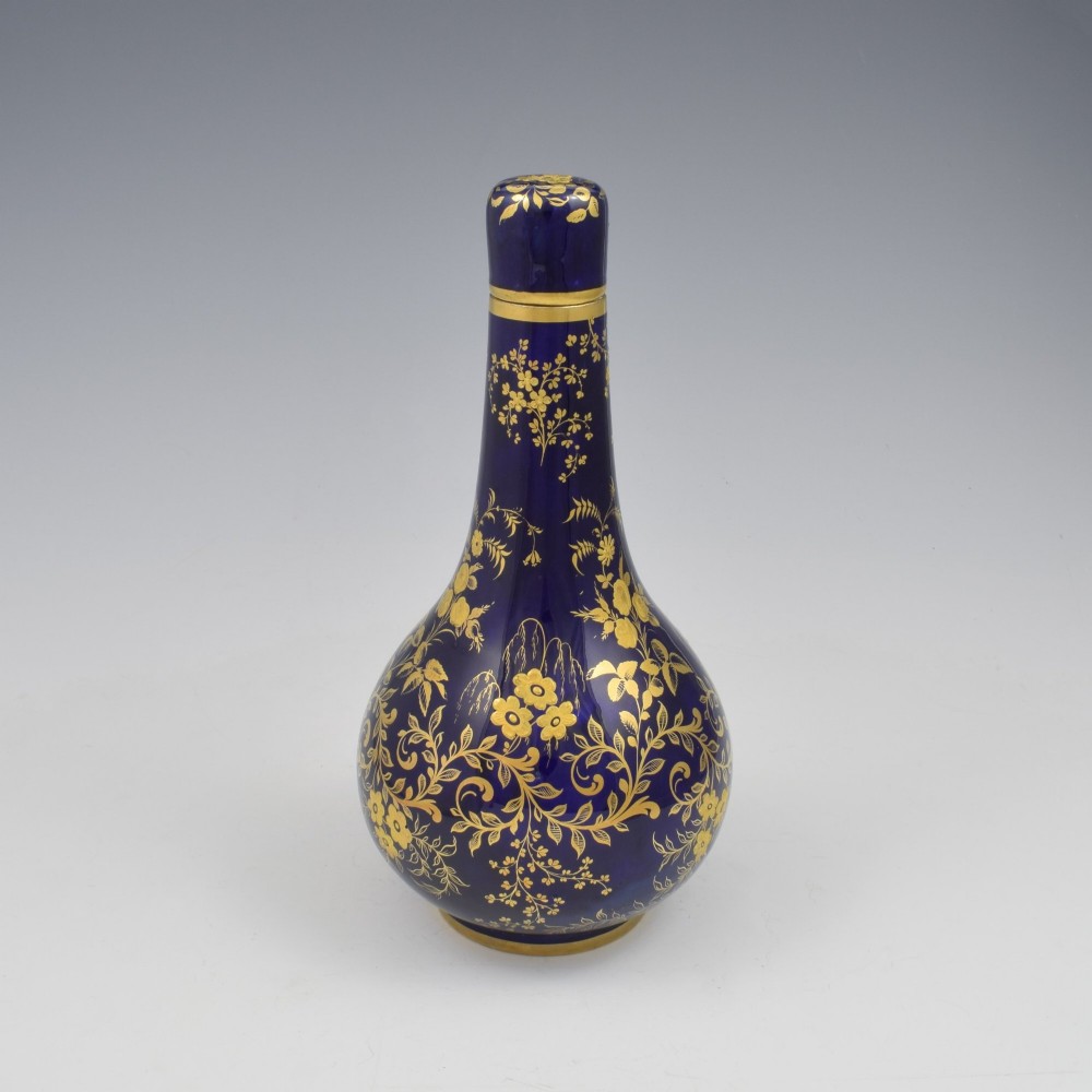 A cobalt blue porcelain bottle vase decorated with elaborate gold floral gilding and fitted with a matching rounded stopper. View IV