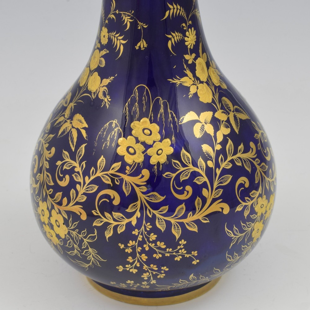 A cobalt blue porcelain bottle vase decorated with elaborate gold floral gilding and fitted with a matching rounded stopper. View V
