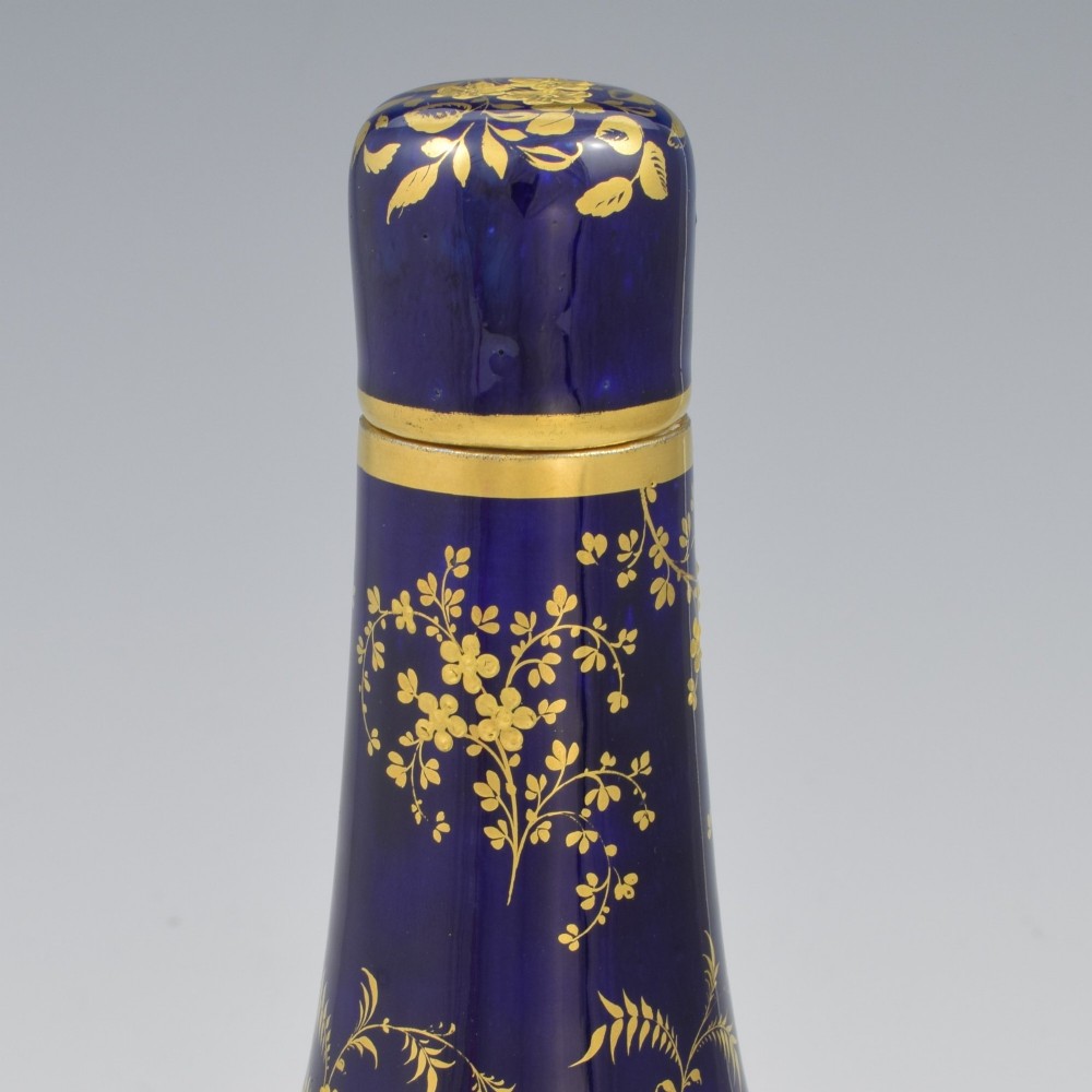 A cobalt blue porcelain bottle vase decorated with elaborate gold floral gilding and fitted with a matching rounded stopper. View VI