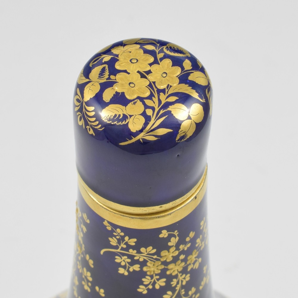 A cobalt blue porcelain bottle vase decorated with elaborate gold floral gilding and fitted with a matching rounded stopper. View IX
