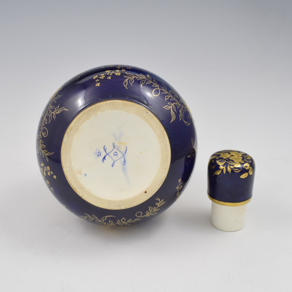 A cobalt blue porcelain bottle vase decorated with elaborate gold floral gilding and fitted with a matching rounded stopper. View XII