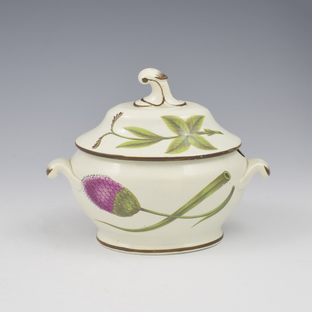 A Georgian cream pearlware lidded sauce tureen hand painted with botanical flowers and featuring scroll handles and a scroll finial. View IV