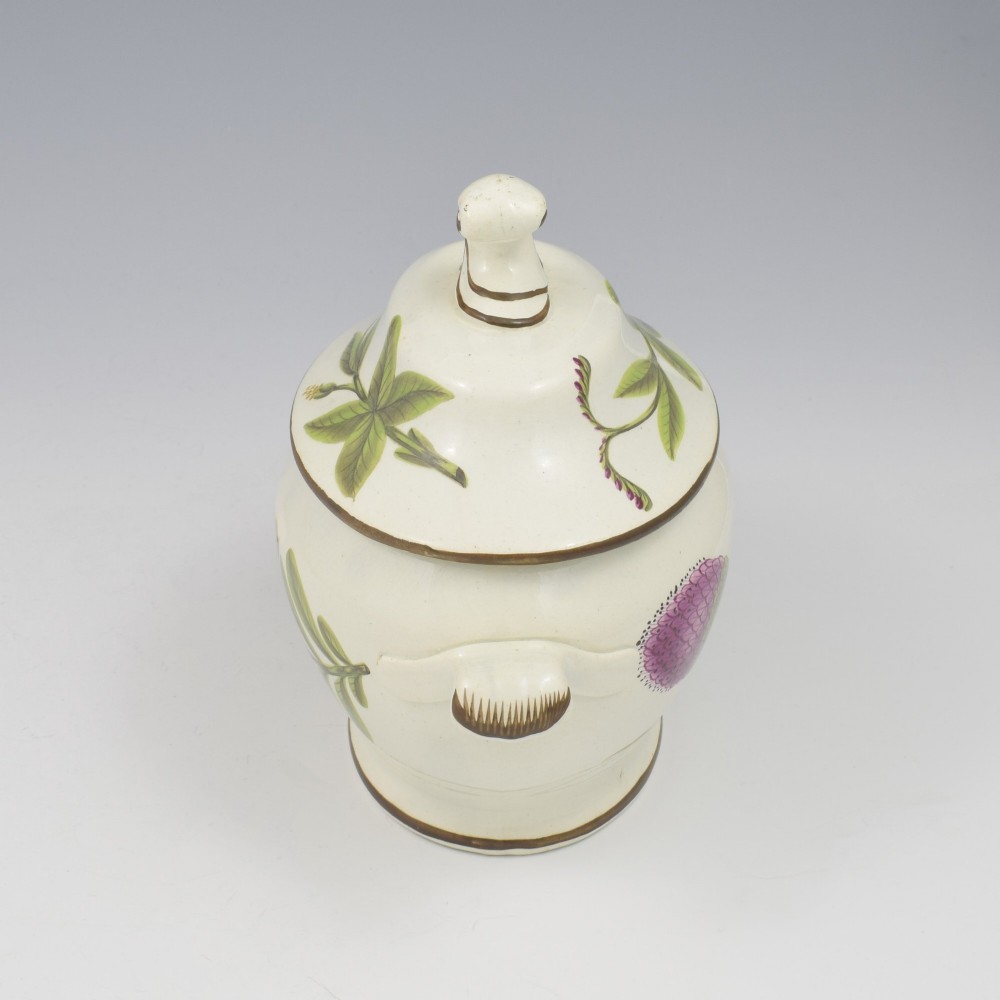 A Georgian cream pearlware lidded sauce tureen hand painted with botanical flowers and featuring scroll handles and a scroll finial. View VI