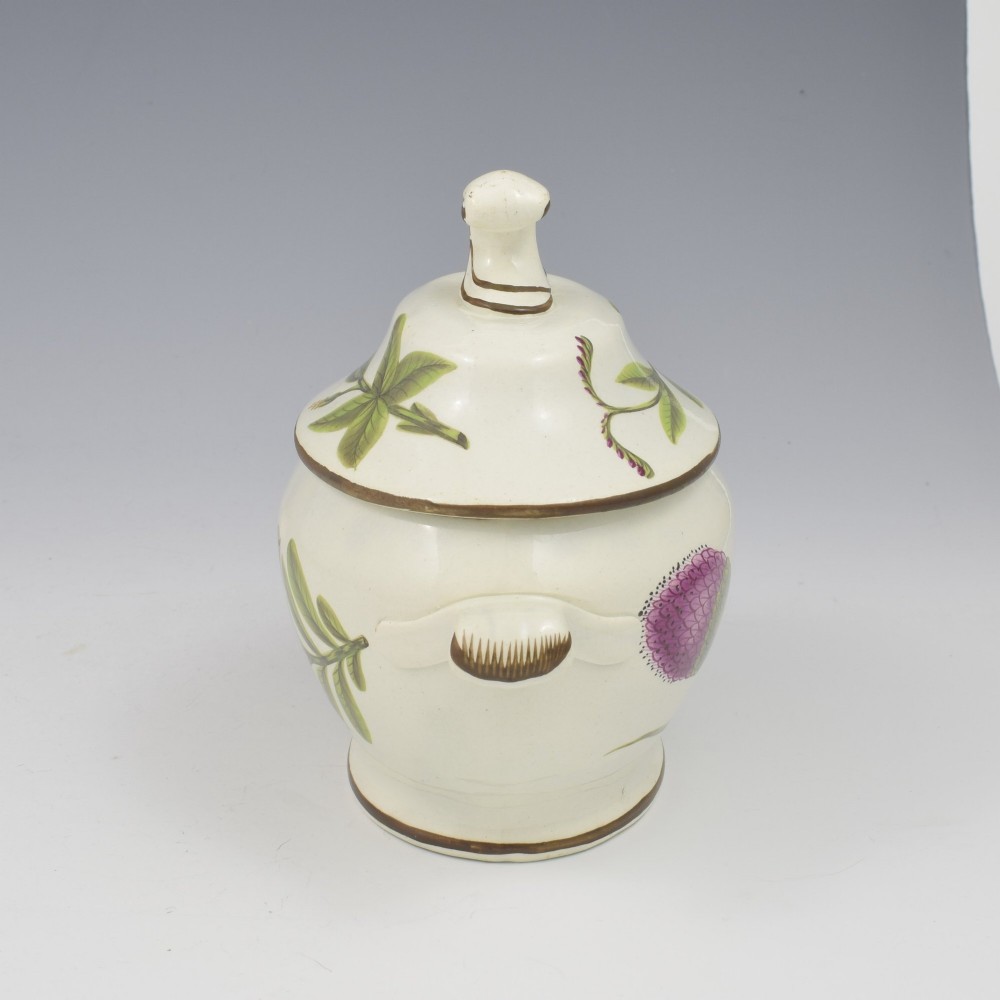 A Georgian cream pearlware lidded sauce tureen hand painted with botanical flowers and featuring scroll handles and a scroll finial. View VII