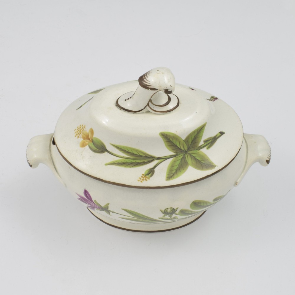 A Georgian cream pearlware lidded sauce tureen hand painted with botanical flowers and featuring scroll handles and a scroll finial. View VIII