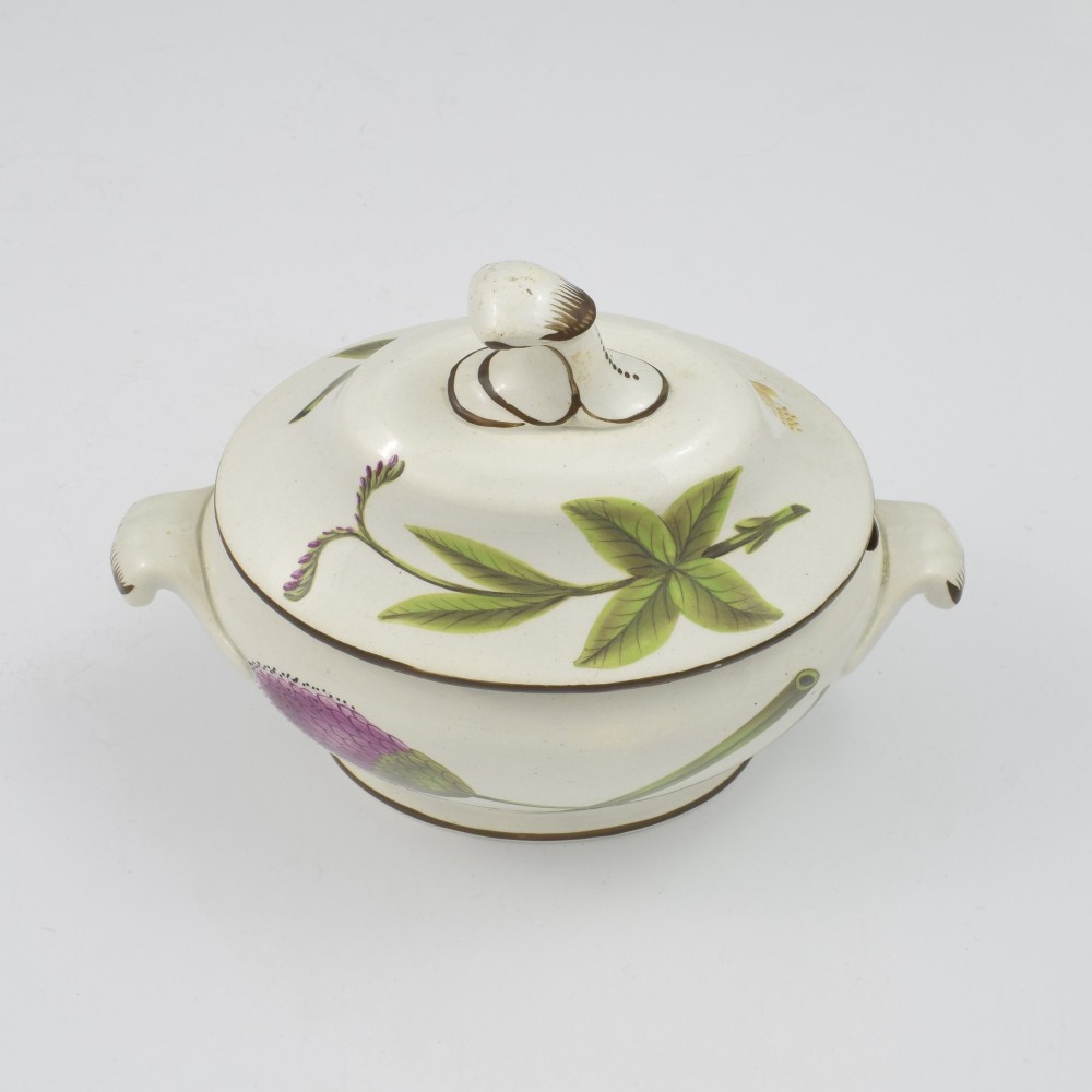 A Georgian cream pearlware lidded sauce tureen hand painted with botanical flowers and featuring scroll handles and a scroll finial. View IX