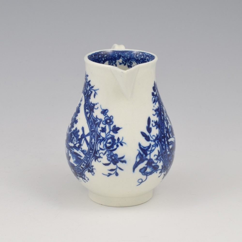 A Georgian blue and white soft-paste porcelain cream jug decorated with an underglaze landscape print in a cartouche frame. View II