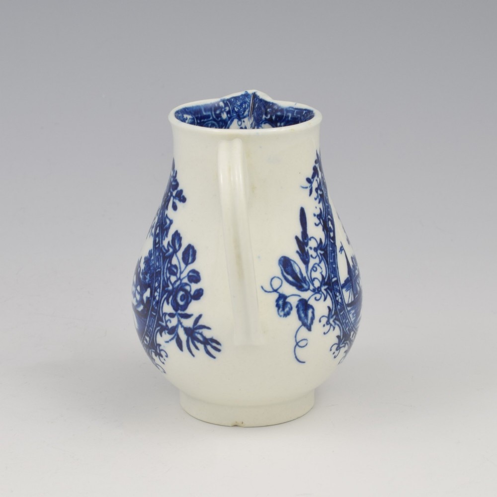 A Georgian blue and white soft-paste porcelain cream jug decorated with an underglaze landscape print in a cartouche frame. View IV