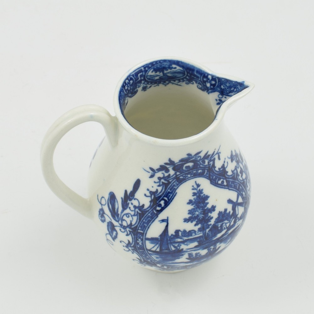 A Georgian blue and white soft-paste porcelain cream jug decorated with an underglaze landscape print in a cartouche frame. View V