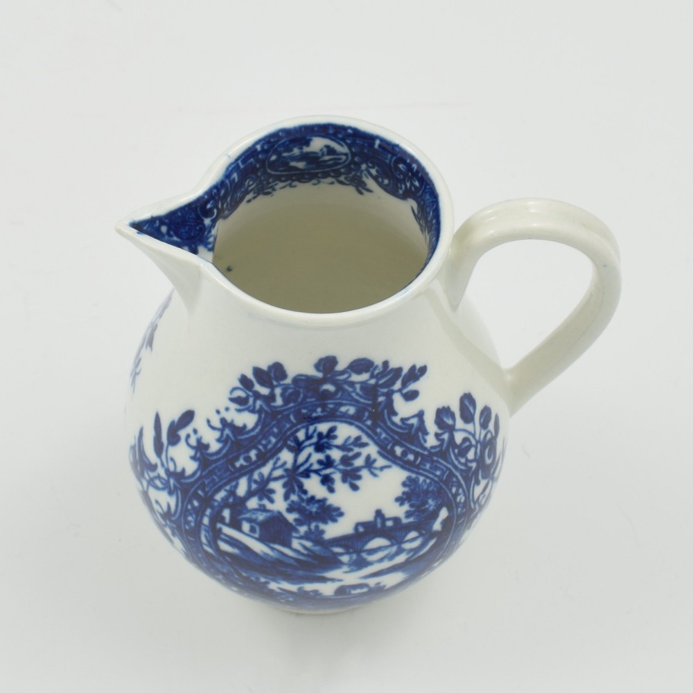 A Georgian blue and white soft-paste porcelain cream jug decorated with an underglaze landscape print in a cartouche frame. View VI