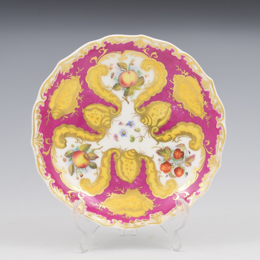 An antique English porcelain tea trio comprising a teacup, coffee cup, and saucer decorated with magenta ground, gilded scrollwork, and hand-painted fruit panels. View III