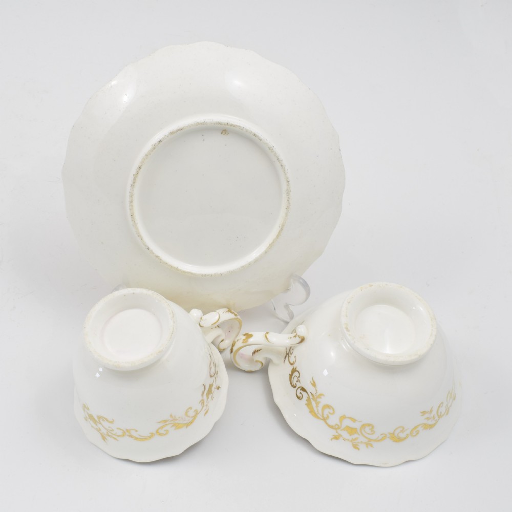 An antique English porcelain tea trio comprising a teacup, coffee cup, and saucer decorated with magenta ground, gilded scrollwork, and hand-painted fruit panels. View XIV