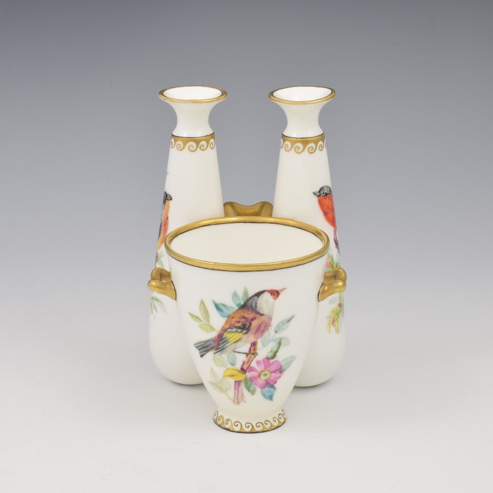 A Victorian white porcelain triple vase featuring three connected vessels decorated with hand-painted birds and gilt trim. View II
