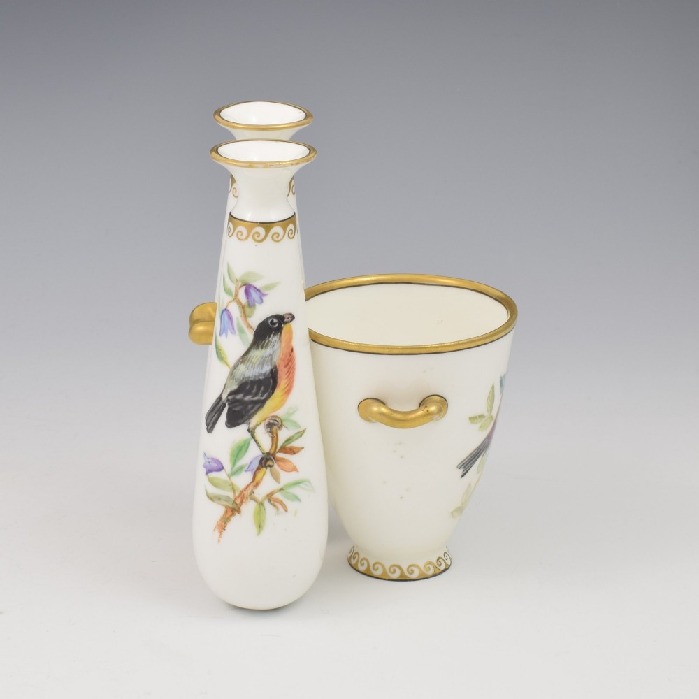 A Victorian white porcelain triple vase featuring three connected vessels decorated with hand-painted birds and gilt trim. View V