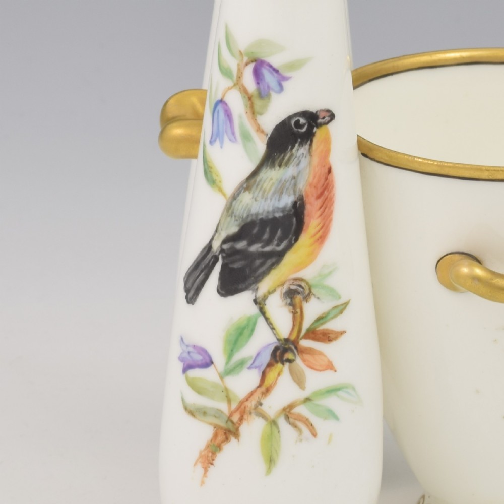 A Victorian white porcelain triple vase featuring three connected vessels decorated with hand-painted birds and gilt trim. View VI