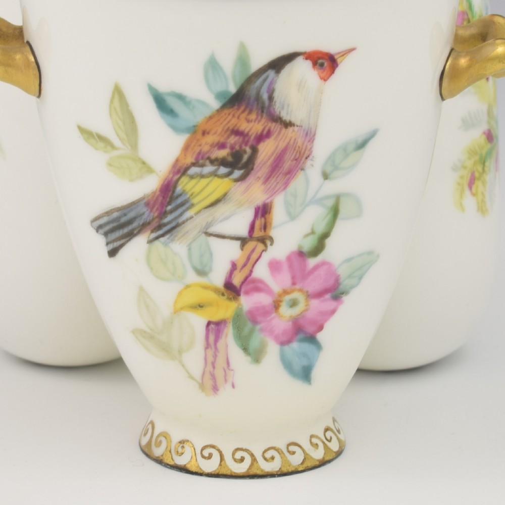 A Victorian white porcelain triple vase featuring three connected vessels decorated with hand-painted birds and gilt trim. View VII
