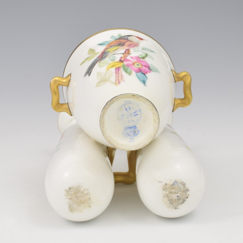 A Victorian white porcelain triple vase featuring three connected vessels decorated with hand-painted birds and gilt trim. View IX