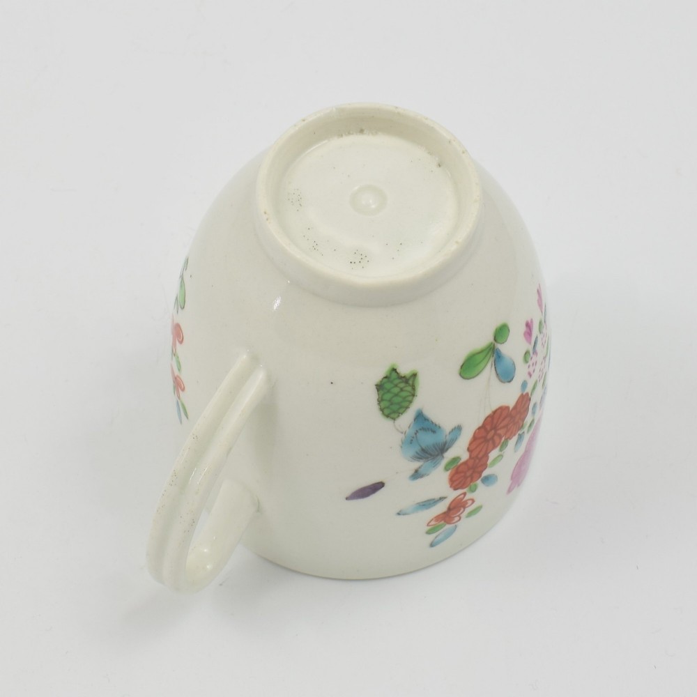 An 18th-century white porcelain coffee cup decorated with hand-painted polychrome floral sprays and an inner red patterned border. View VI