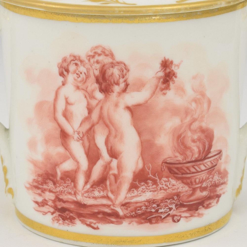 A white Regency period Bloor Derby porcelain chocolate cup featuring twin handles, a fitted lid with a loop finial, hand-painted sepia putti, and gold gilded leaf borders. View VIII