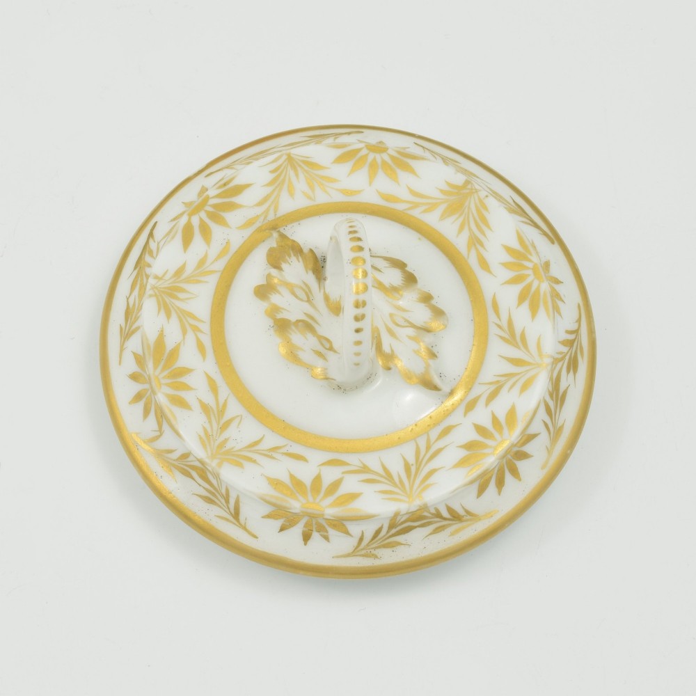 A white Regency period Bloor Derby porcelain chocolate cup featuring twin handles, a fitted lid with a loop finial, hand-painted sepia putti, and gold gilded leaf borders. View IX