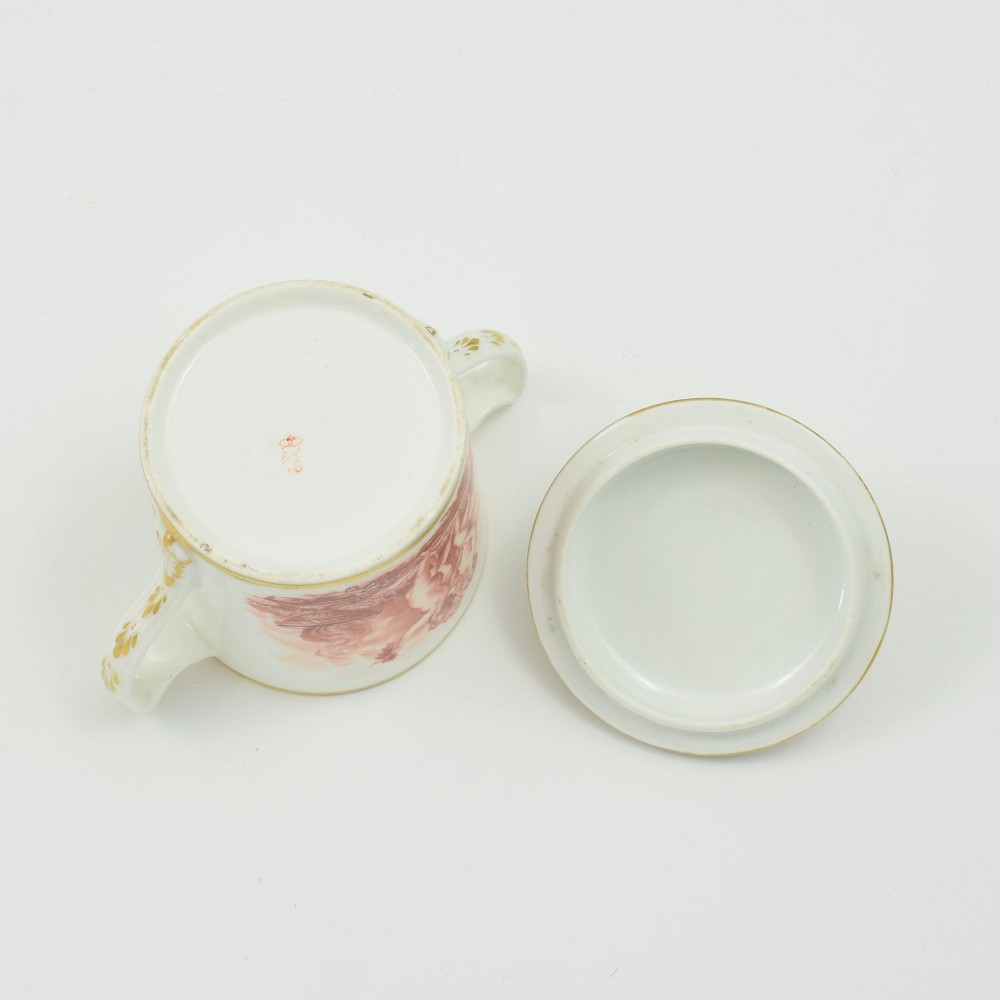A white Regency period Bloor Derby porcelain chocolate cup featuring twin handles, a fitted lid with a loop finial, hand-painted sepia putti, and gold gilded leaf borders. View XI