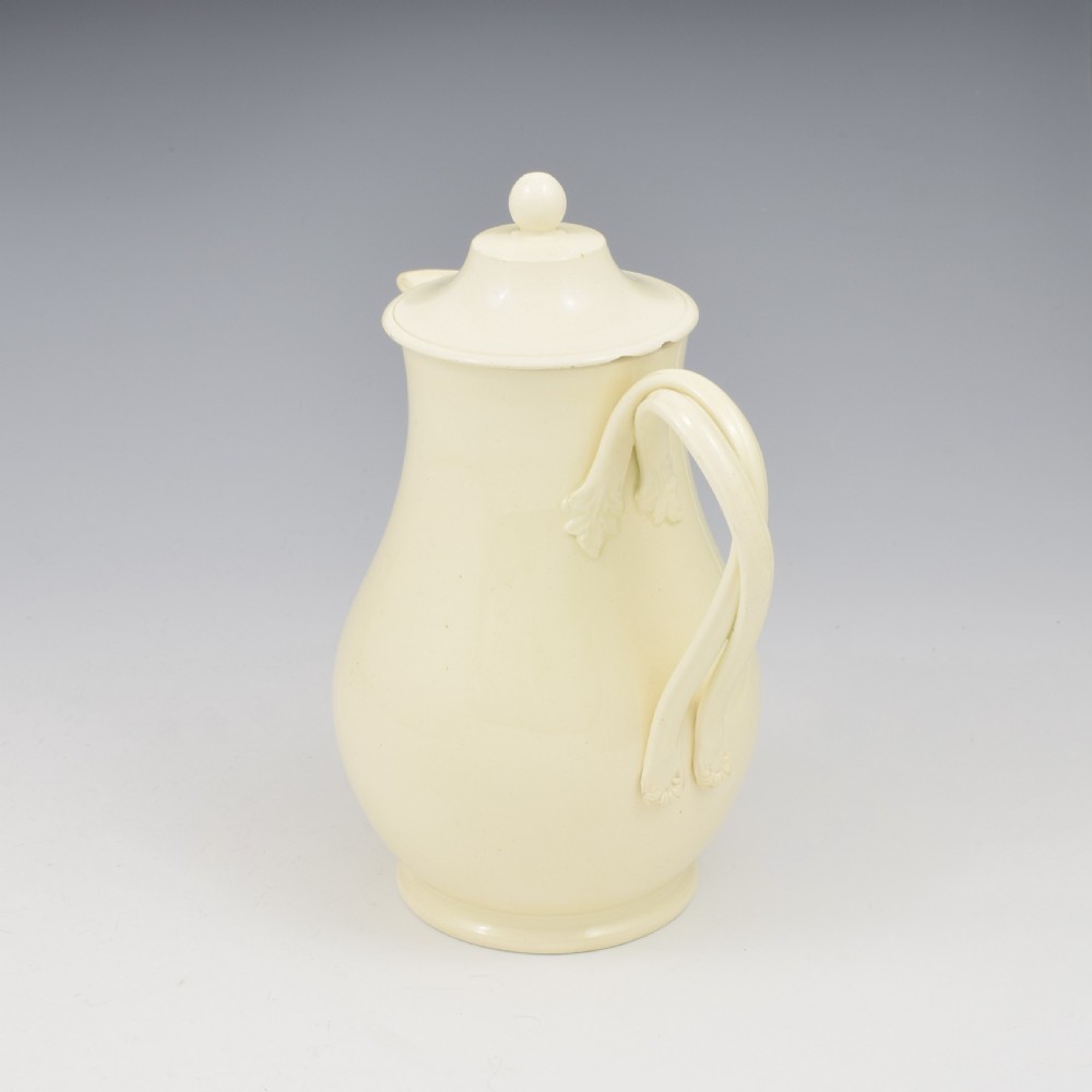 An 18th-century creamware hot water jug featuring a baluster-shaped earthenware body, a fitted dome cover with a ball finial, and a loop handle. View III