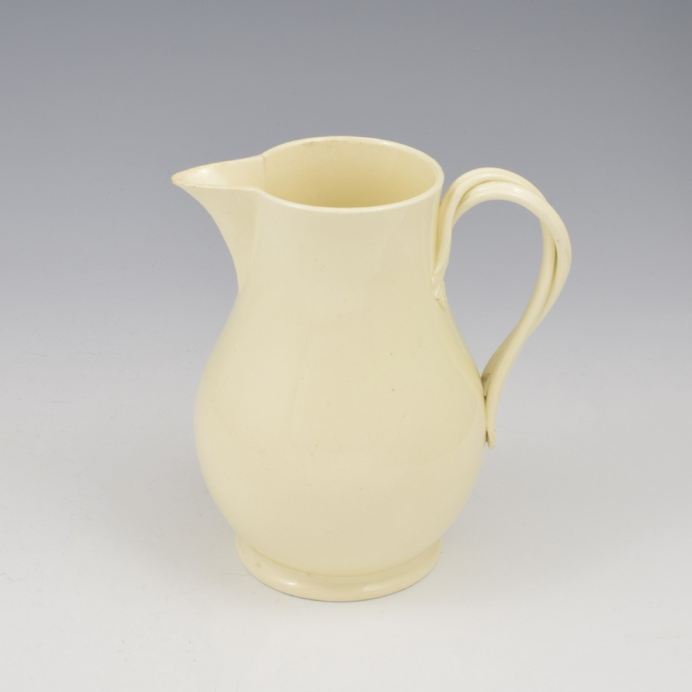 An 18th-century creamware hot water jug featuring a baluster-shaped earthenware body, a fitted dome cover with a ball finial, and a loop handle. View XII