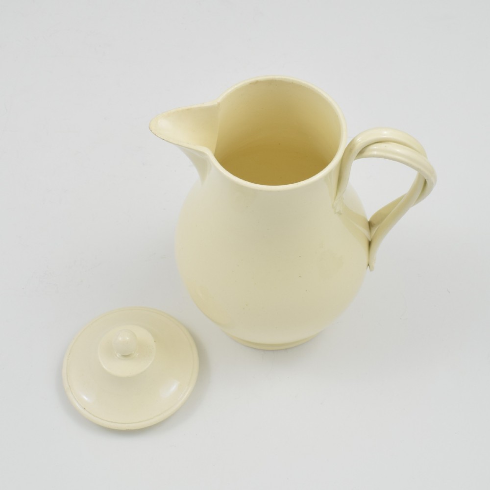 An 18th-century creamware hot water jug featuring a baluster-shaped earthenware body, a fitted dome cover with a ball finial, and a loop handle. View XIV