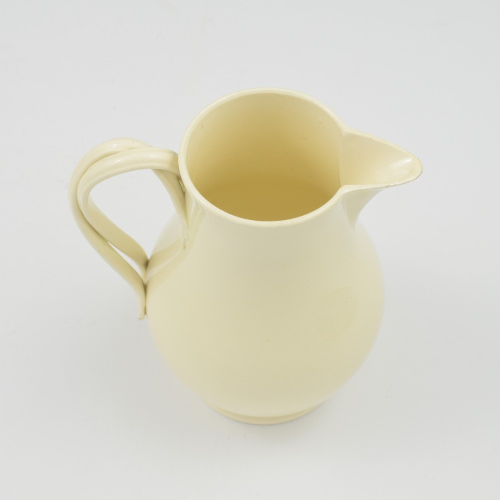 An 18th-century creamware hot water jug featuring a baluster-shaped earthenware body, a fitted dome cover with a ball finial, and a loop handle. View XV