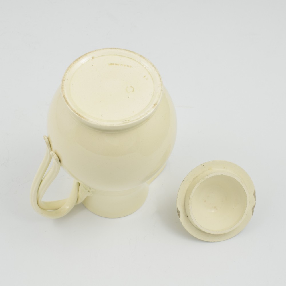 An 18th-century creamware hot water jug featuring a baluster-shaped earthenware body, a fitted dome cover with a ball finial, and a loop handle. View XVI