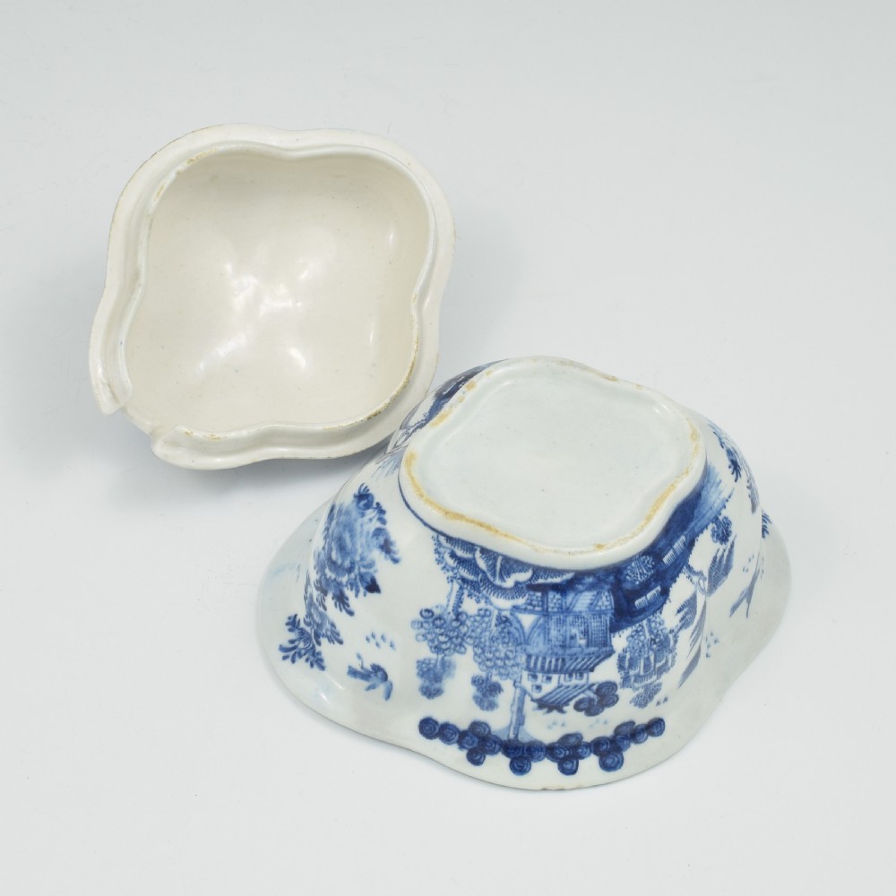 An eighteenth-century Derby soft-paste porcelain sauce tureen and cover featuring a quatrefoil shape, hand-painted blue and white Chinoiserie decoration, and a sculpted fruit handle on the lid. View XII