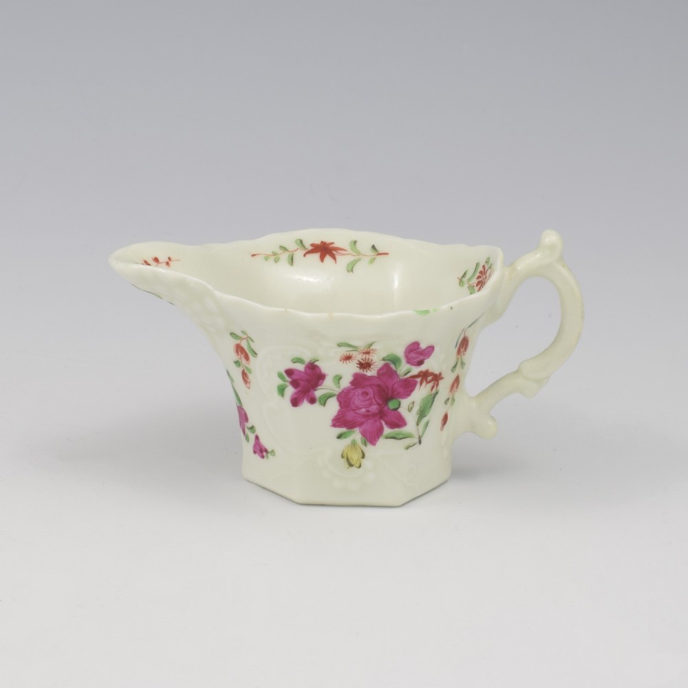 An 18th-century soft-paste porcelain hexagonal sauce boat featuring hand-painted pink floral sprays and a molded scroll handle.