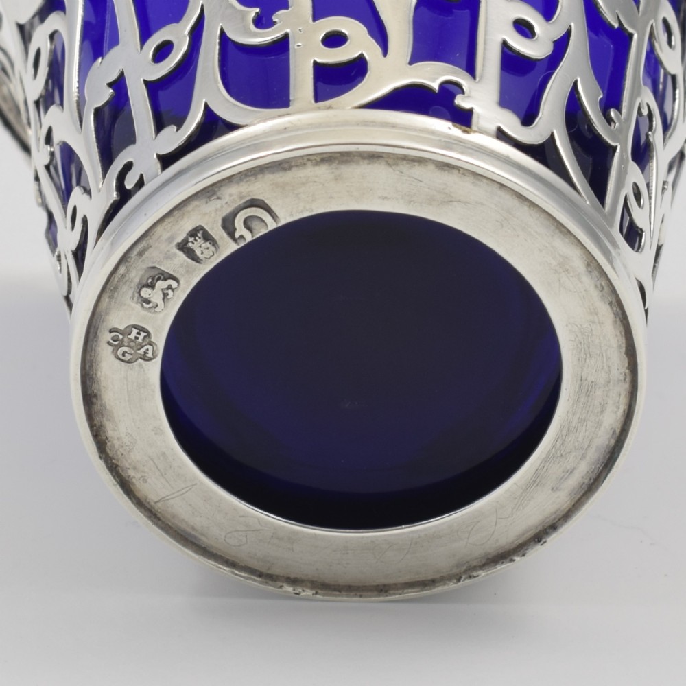 An 18th-century Georgian pierced sterling silver cream pail featuring intricate foliage scrollwork, a swing handle, and a removable cobalt blue glass liner. View IX