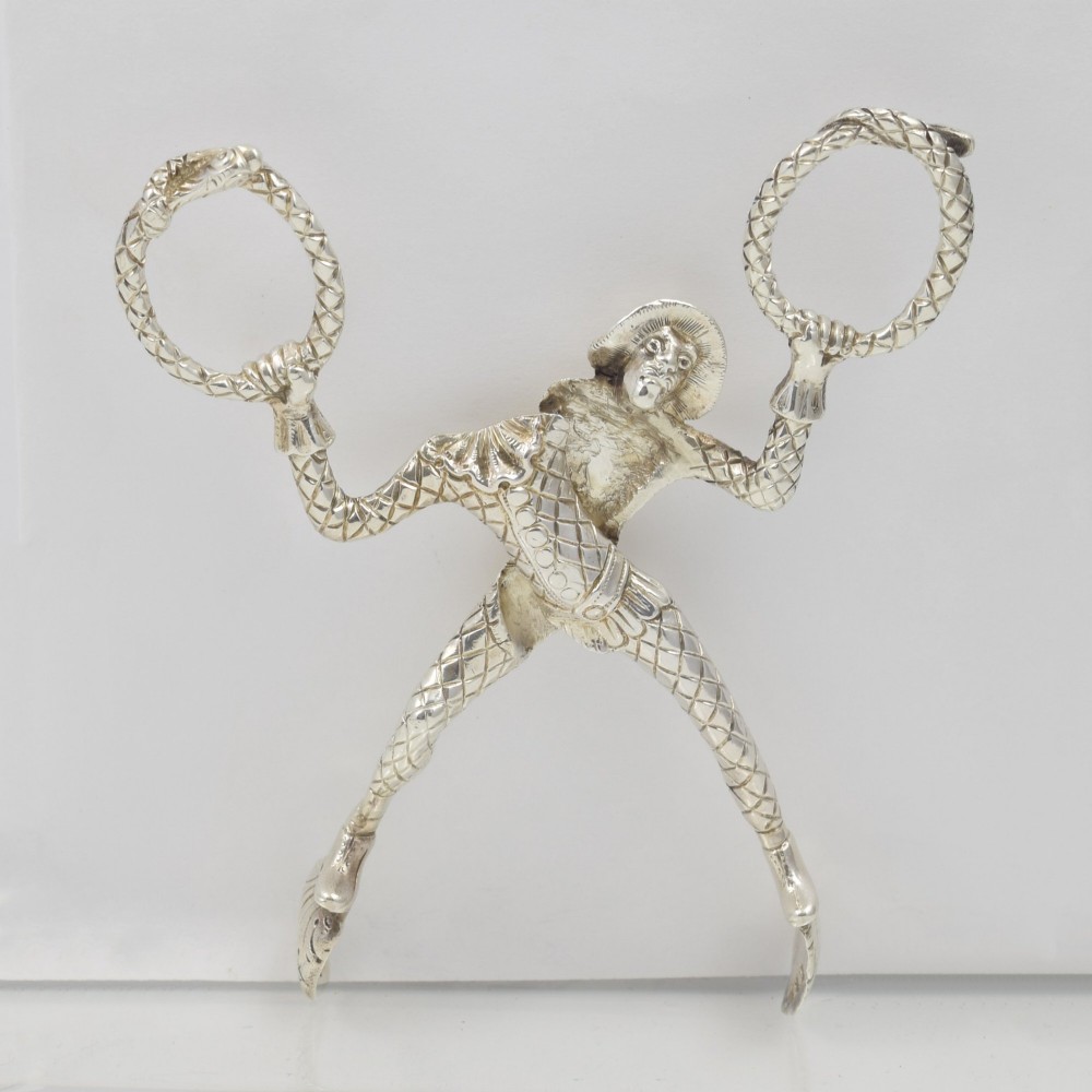A George IV sterling silver novelty sugar tong designed as a Harlequin figure holding circular ring handles above its head. View III