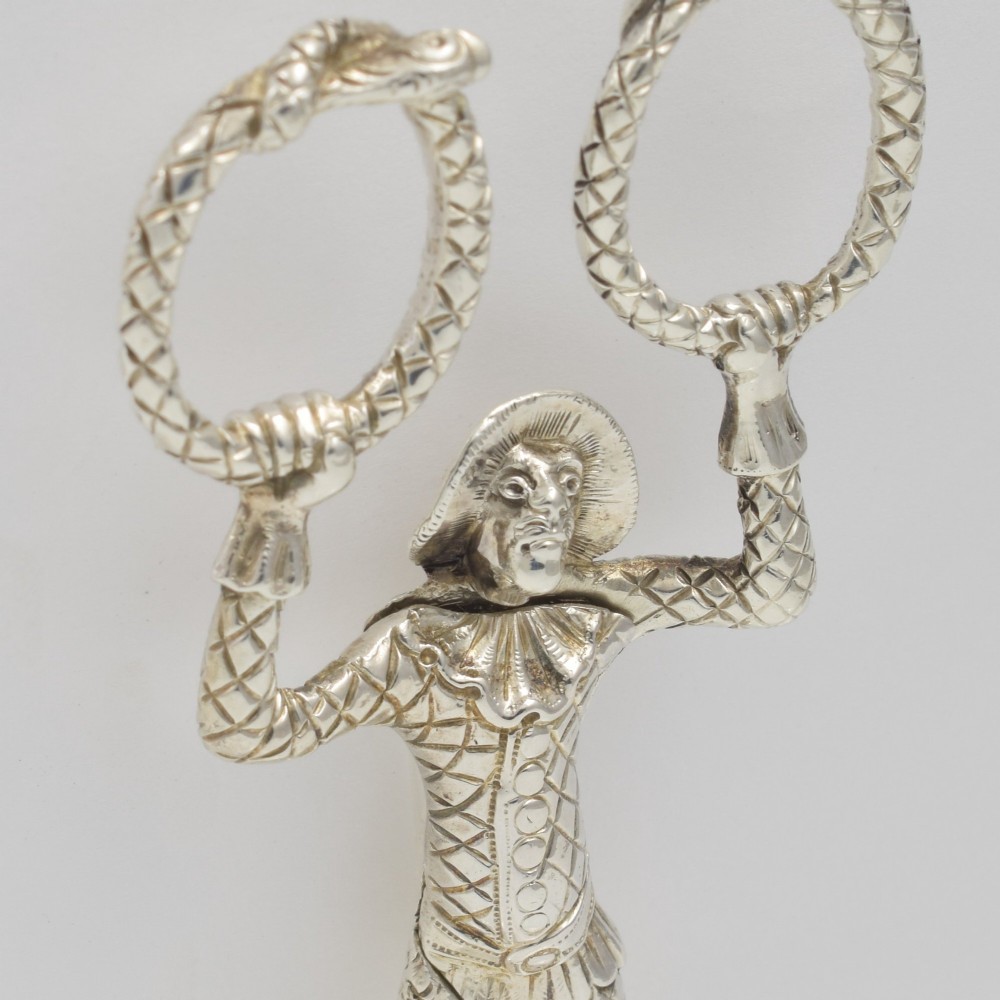 A George IV sterling silver novelty sugar tong designed as a Harlequin figure holding circular ring handles above its head. View VII