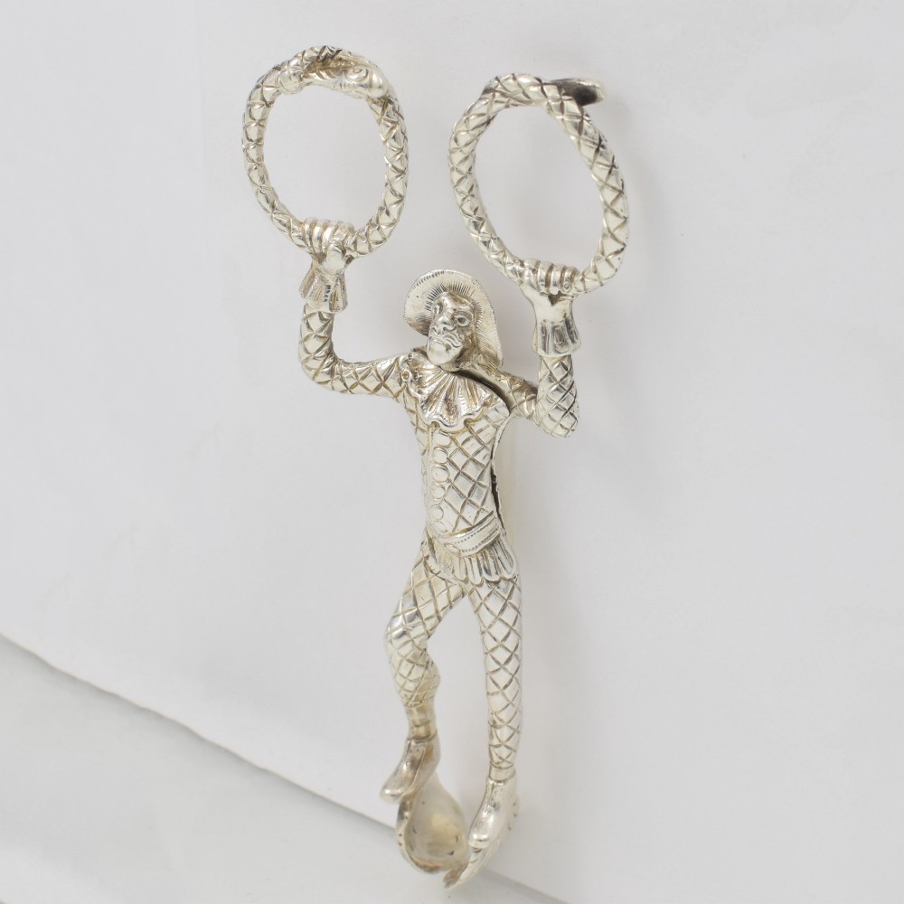 A George IV sterling silver novelty sugar tong designed as a Harlequin figure holding circular ring handles above its head. View VIII