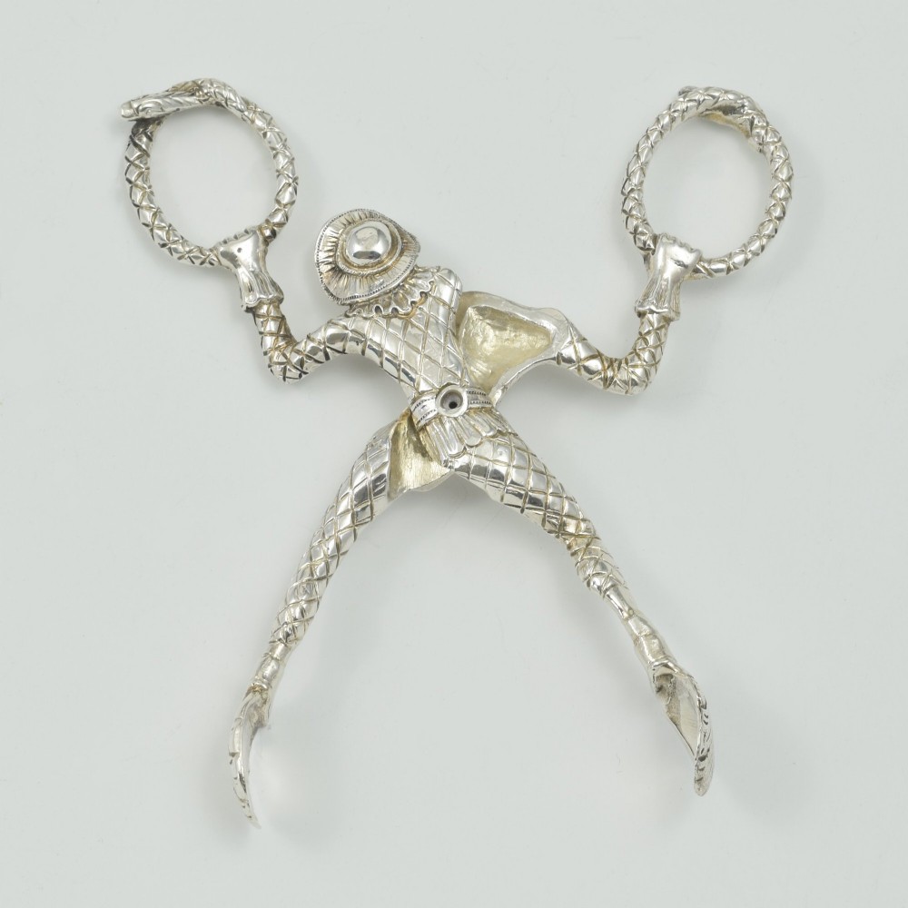 A George IV sterling silver novelty sugar tong designed as a Harlequin figure holding circular ring handles above its head. View XII