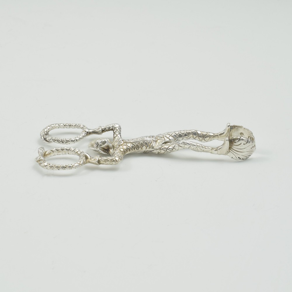 A George IV sterling silver novelty sugar tong designed as a Harlequin figure holding circular ring handles above its head. View XIII