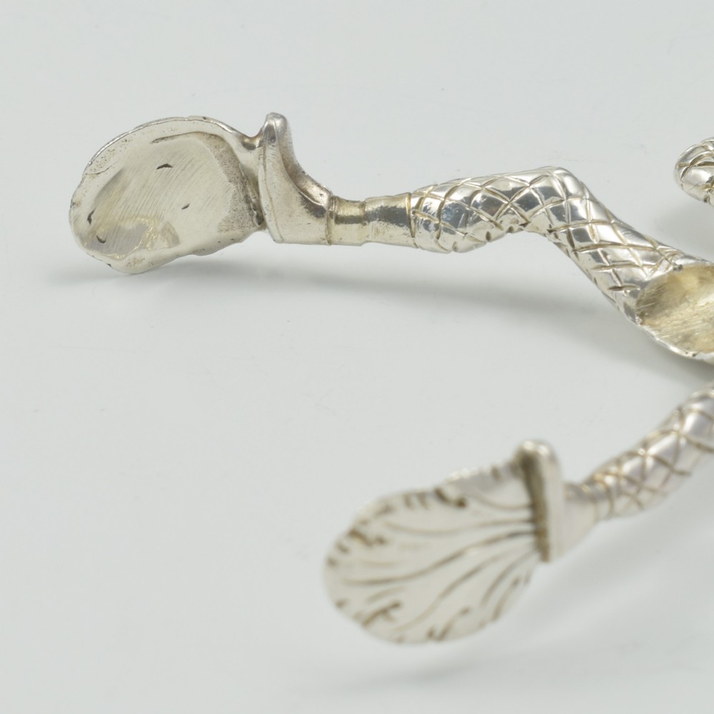A George IV sterling silver novelty sugar tong designed as a Harlequin figure holding circular ring handles above its head. View XV