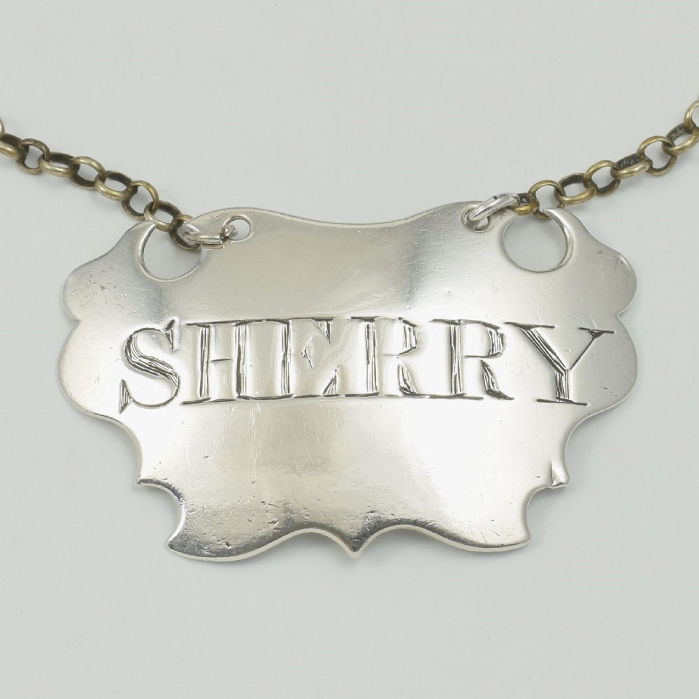A Georgian sterling silver escutcheon-shaped decanter label engraved with the word SHERRY, featuring a suspension chain. View II