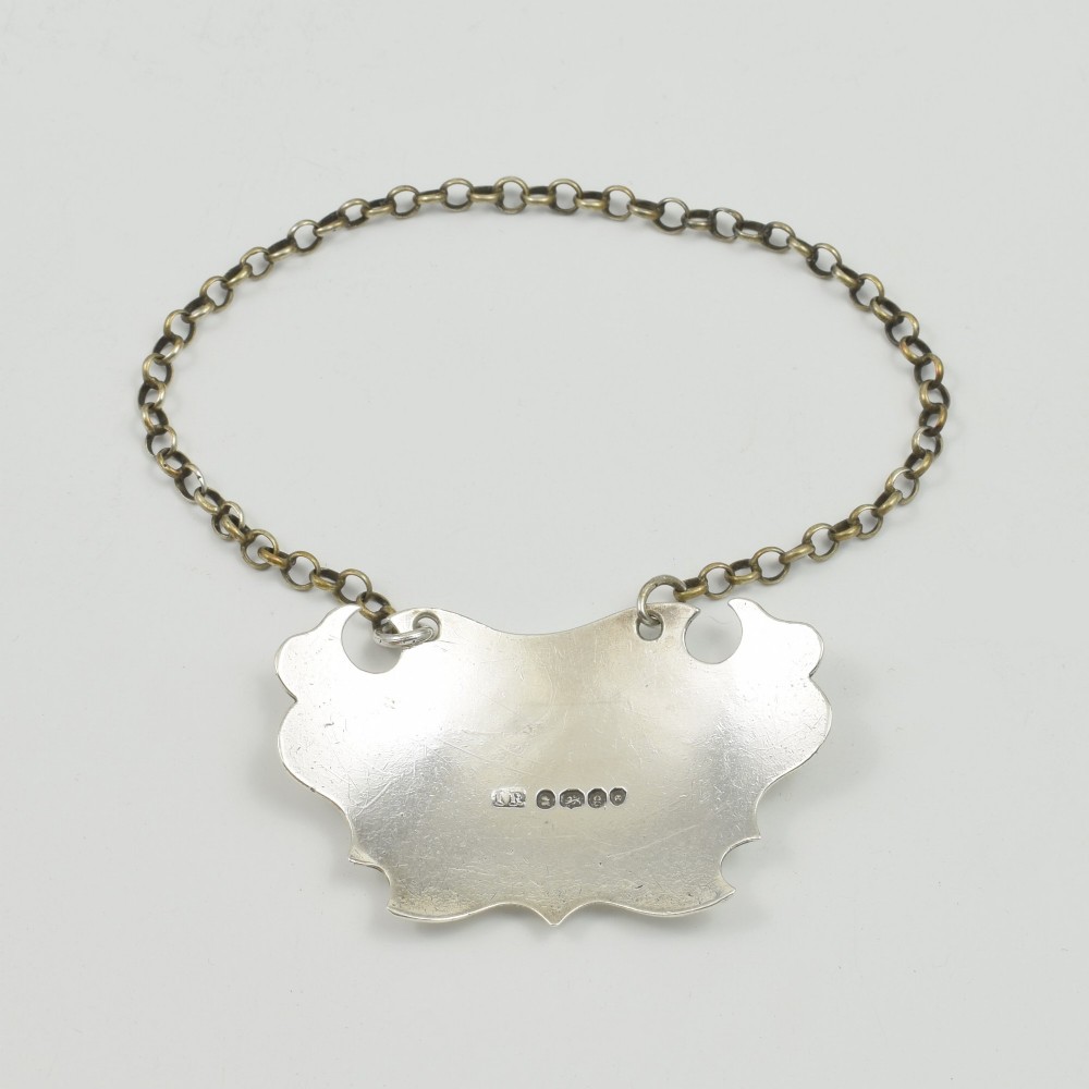 A Georgian sterling silver escutcheon-shaped decanter label engraved with the word SHERRY, featuring a suspension chain. View IV
