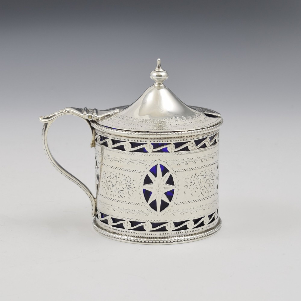 A Victorian silver drum mustard pot with pierced fretwork, bright-cut engraving, a hinged lid, and a cobalt blue glass liner.