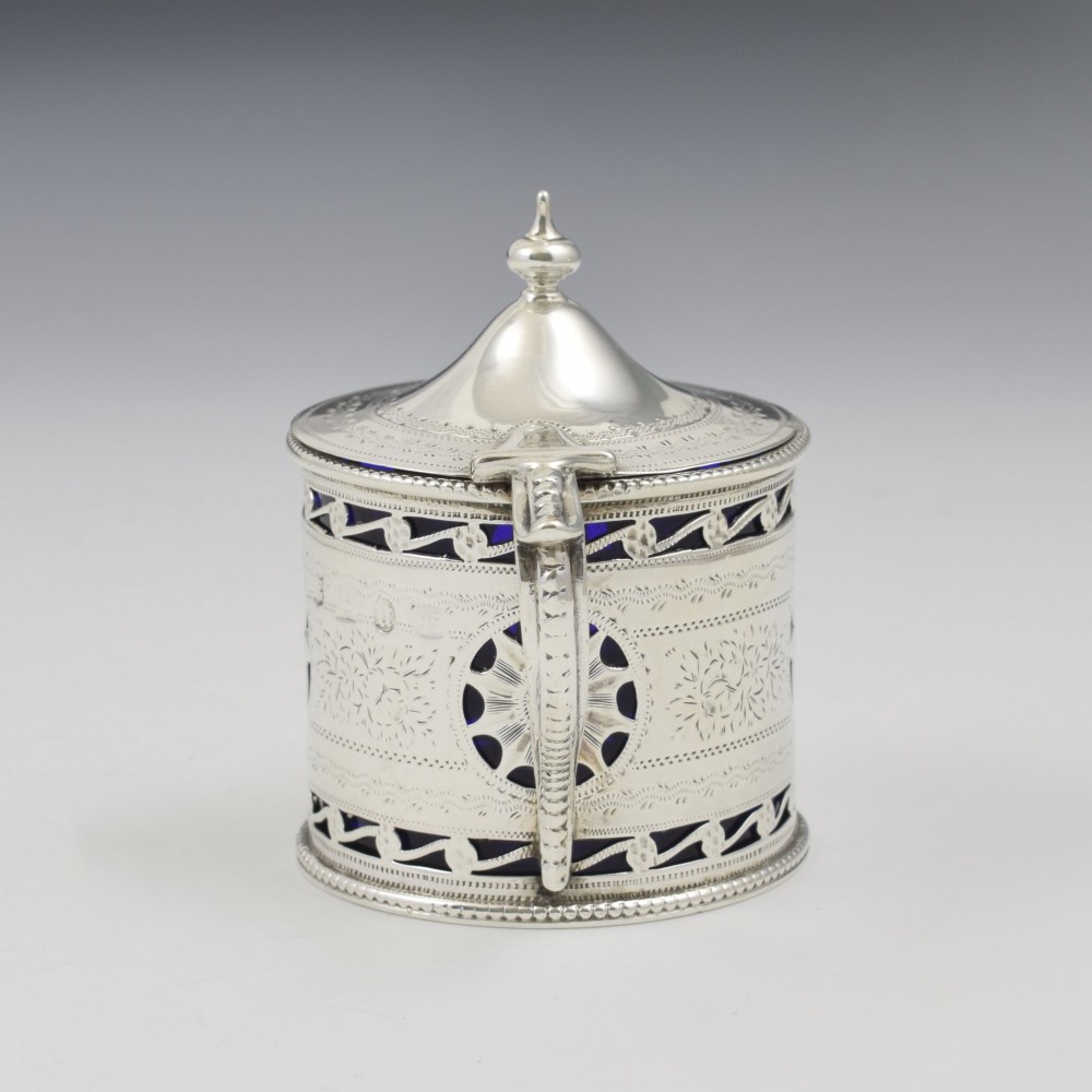 A Victorian silver drum mustard pot with pierced fretwork, bright-cut engraving, a hinged lid, and a cobalt blue glass liner. View V