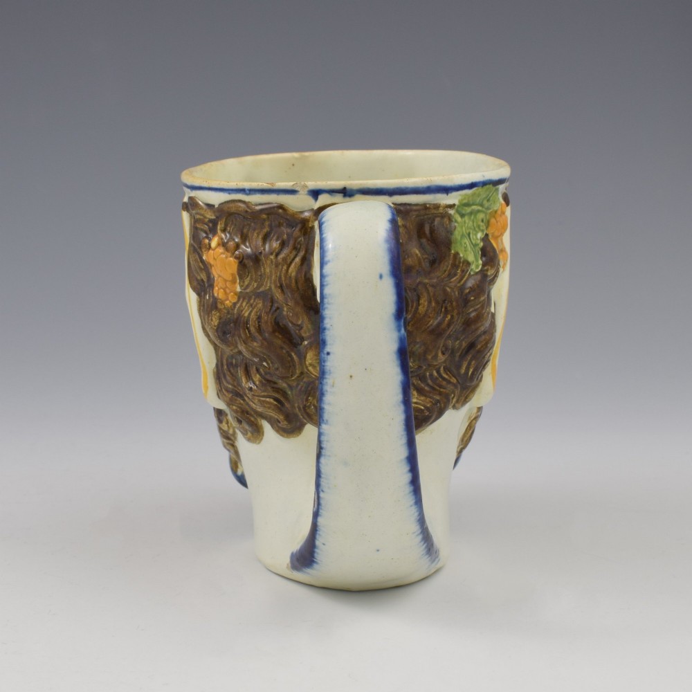 A late 18th-century pearlware ceramic mug formed as a satyrs head with relief-moulded beard, pointed ears, and grapevines in underglaze colours. View VII
