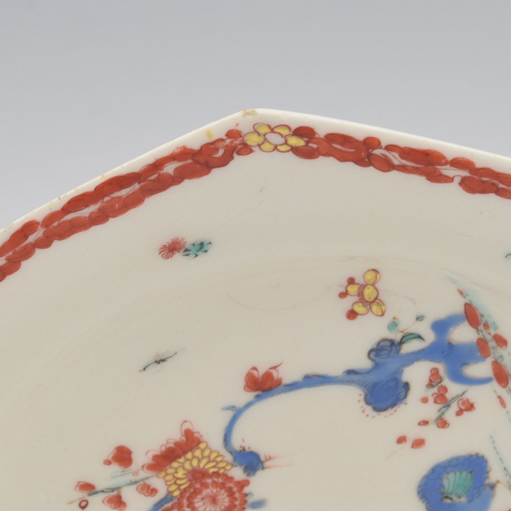 An 18th-century octagonal soft-paste porcelain plate decorated with iron-red and blue enamels showing two quails under flowering branches within a red scroll border. View VII