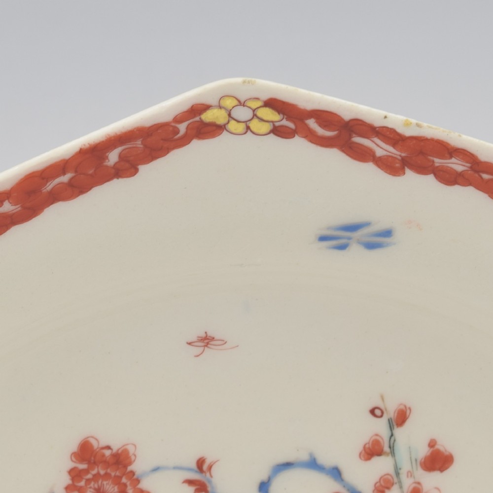 An 18th-century octagonal soft-paste porcelain plate decorated with iron-red and blue enamels showing two quails under flowering branches within a red scroll border. View VIII