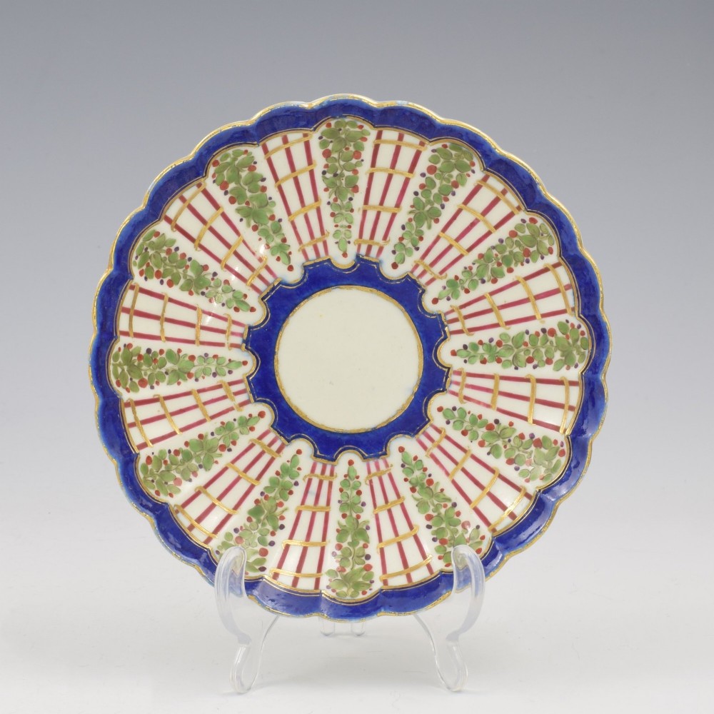 An 18th-century soft-paste porcelain coffee cup and saucer with fluted edges, featuring a cobalt blue border, gilt highlights, and a painted green hop trellis pattern. View II